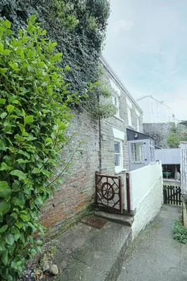 a brick building with a gate on the side of it at Well Court is a fabulous cottage with wonderful views set in the heart of Polruan village in Fowey