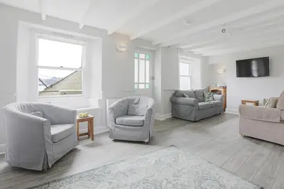 a living room with two chairs and a tv at Well Court is a fabulous cottage with wonderful views set in the heart of Polruan village in Fowey