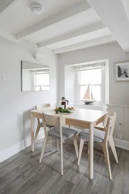a white dining room with a table and chairs at Well Court is a fabulous cottage with wonderful views set in the heart of Polruan village in Fowey