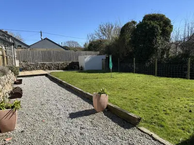 a backyard with a yard with a fence and some plants at Hideaway Barn in Germoe