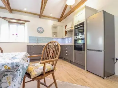 a kitchen with a table and a refrigerator at Hideaway Barn in Germoe