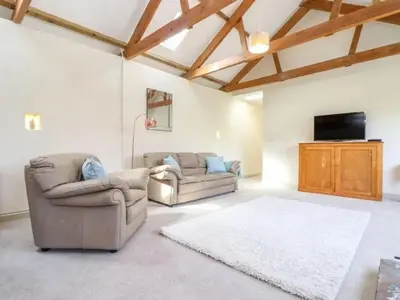 a living room with two couches and a flat screen tv at Hideaway Barn in Germoe