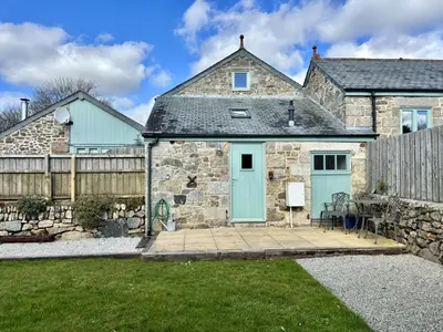 a stone house with blue doors and a fence at Hideaway Barn in Germoe