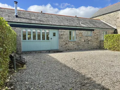a stone house with a blue garage at Hideaway Barn in Germoe