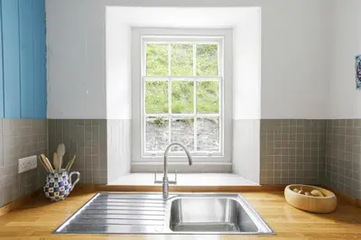 a kitchen with a sink and a window at Coastguard Cottage - set in an elevated position with fabulous views overlooking Portloe in Portloe