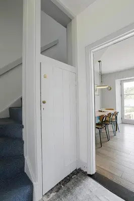 a white hallway with a dining room with a table at Coastguard Cottage - set in an elevated position with fabulous views overlooking Portloe in Portloe