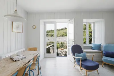 a dining room with a table and blue chairs at Coastguard Cottage - set in an elevated position with fabulous views overlooking Portloe in Portloe
