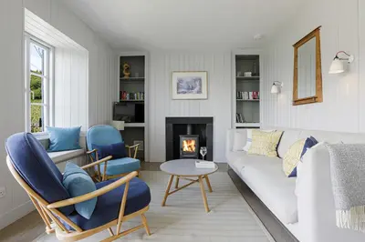 a living room with a white couch and a fireplace at Coastguard Cottage - set in an elevated position with fabulous views overlooking Portloe in Portloe