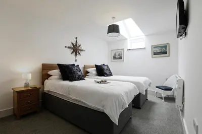 a bedroom with a large bed and a chair at Trekenna close to Marazion and Praa Sands in Saint Hilary