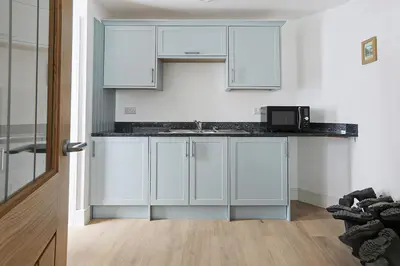 a kitchen with white cabinets and a microwave at Trekenna close to Marazion and Praa Sands in Saint Hilary