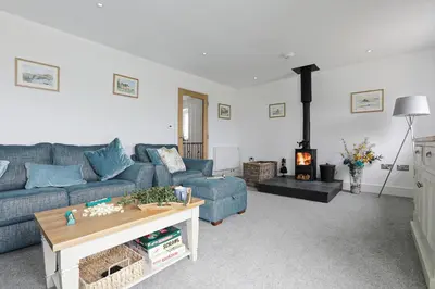 a living room with a blue couch and a fireplace at Trekenna close to Marazion and Praa Sands in Saint Hilary