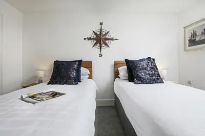 two beds in a room with white sheets and blue pillows at Trekenna close to Marazion and Praa Sands in Saint Hilary