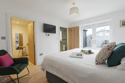a bedroom with a bed and a chair and a television at Trekenna close to Marazion and Praa Sands in Saint Hilary