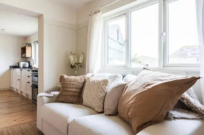 a white couch in a living room with windows at Longstone at Bogee Farm in Saint Ervan