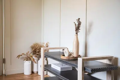 a black shelf with vases on it next to a chair at Longstone at Bogee Farm in Saint Ervan