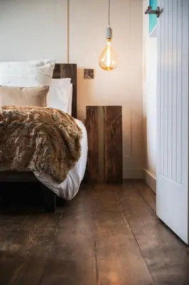 a bedroom with a bed and a wooden floor at Longstone at Bogee Farm in Saint Ervan