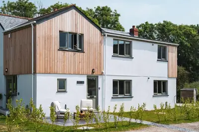 a white house with a wooden roof and windows at Longstone at Bogee Farm in Saint Ervan