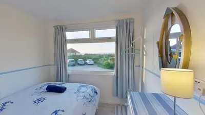 a bedroom with a bed and a large window at E42 Vista Marina, Riviere Towans in Hayle