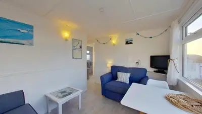 a living room with a blue couch and a table at E42 Vista Marina, Riviere Towans in Hayle