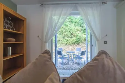 a bed in front of a window with a table and chairs at Trewhiddle Cottage 41 - 1 Bedroom Cottage in St Austell