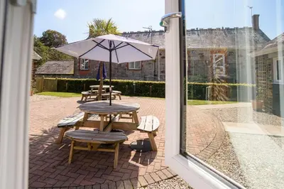 a patio with a table with an umbrella and chairs at Trewhiddle Cottage 41 - 1 Bedroom Cottage in St Austell