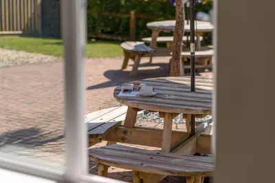 a wooden picnic table with an umbrella on a patio at Trewhiddle Cottage 41 - 1 Bedroom Cottage in St Austell