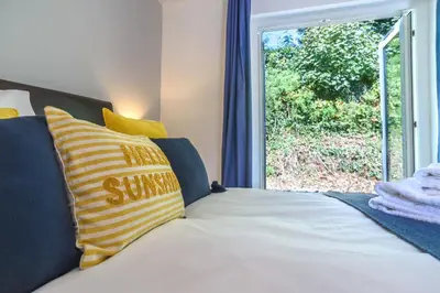 a bed with yellow and blue pillows and a window at Trewhiddle Cottage 41 - 1 Bedroom Cottage in St Austell