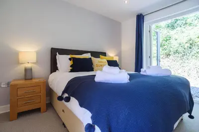 a bedroom with a blue and white bed with a window at Trewhiddle Cottage 41 - 1 Bed Ensuite in St Austell