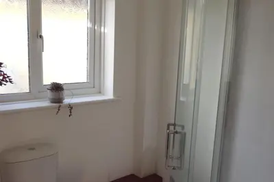 a white bathroom with a window and a toilet at Oxencombe in Davidstow