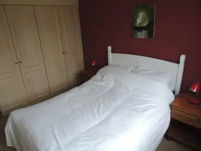 a white bed in a bedroom with a red wall at Oxencombe in Davidstow