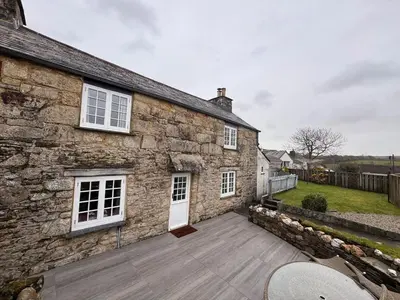 a stone house with a wooden deck in front of it at 3 Double Bed Character Cottage in Quiet Hamlet in Camelford