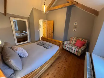 a bedroom with a bed and a couch and a mirror at 3 Double Bed Character Cottage in Quiet Hamlet in Camelford