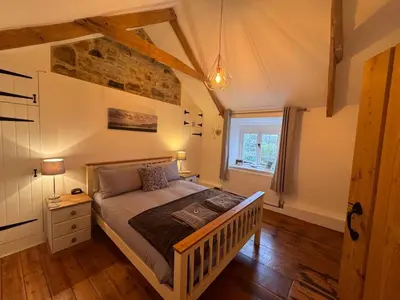 a bedroom with a bed with a wooden floor and a window at 3 Double Bed Character Cottage in Quiet Hamlet in Camelford