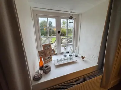 a window sill with vases and a cat sitting on it at 3 Double Bed Character Cottage in Quiet Hamlet in Camelford