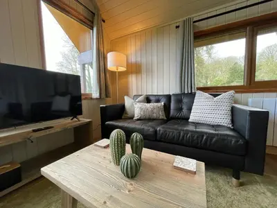 a living room with a black leather couch and a coffee table at RoseTree Lodge 3 bed Sleeps 6 in Michaelstow