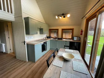 a kitchen with a wooden table and a wooden floor at RoseTree Lodge 3 bed Sleeps 6 in Michaelstow