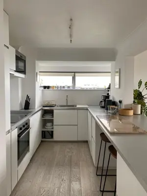 a kitchen with white cabinets and a wooden floor at Stunning Sea View Apartment in Falmouth