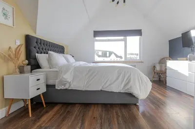 a bedroom with a large bed and a white dresser at Stylish 3-Bed Home - 2 Mins to Beach & Town in Falmouth