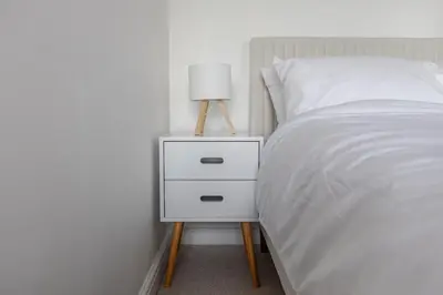 a bed with a night stand with a lamp on it at Stylish 3-Bed Home - 2 Mins to Beach & Town in Falmouth