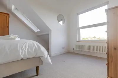 a white bedroom with a bed and a window at Stylish 3-Bed Home - 2 Mins to Beach & Town in Falmouth