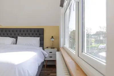a bedroom with a bed and a large window at Stylish 3-Bed Home - 2 Mins to Beach & Town in Falmouth