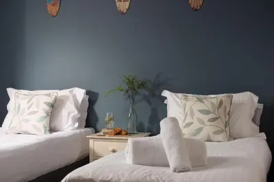 a room with two beds and a table with a chair at Little Beachside in Newquay