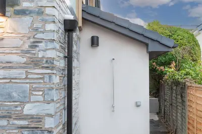 a white garage door with a stone wall at Little Beachside in Newquay