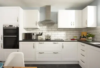 a white kitchen with white cabinets and appliances at Little Puffin Way in Hayle