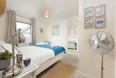 a white bedroom with a bed and a fan at Little Puffin Way in Hayle
