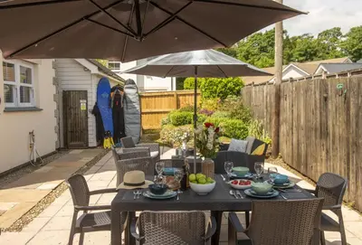a table and chairs with an umbrella on a patio at Little Puffin Way in Hayle