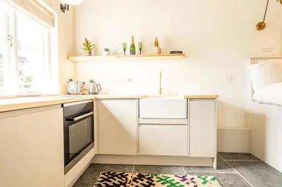 a kitchen with white cabinets and a sink and a window at Romantic and stylish retreat in Falmouth