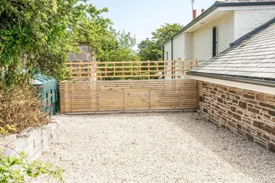 a backyard with a wooden fence next to a house at Romantic and stylish retreat in Falmouth