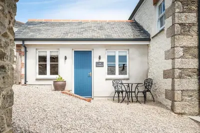 a cottage with a blue door and a table and chairs at Romantic and stylish retreat in Falmouth