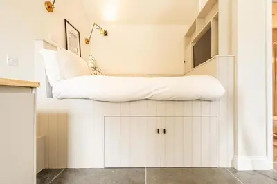 a room with white cabinets and a tv on a wall at Romantic and stylish retreat in Falmouth